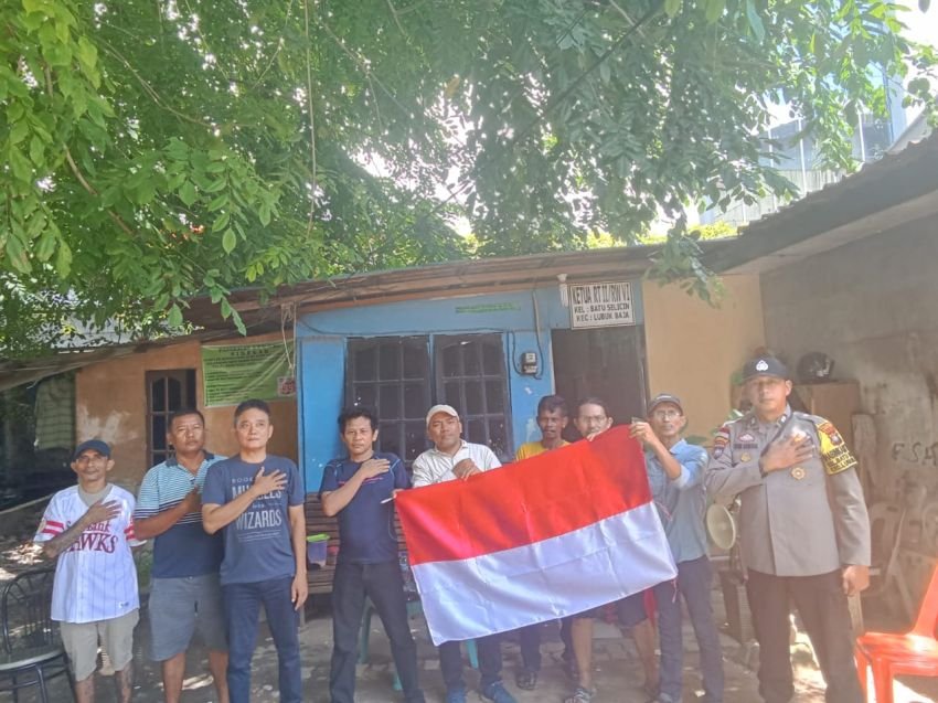 Sambut HUT RI Ke-80, Bhabinkamtibmas Batu Selicin Serahkan Bendera Merah Putih Pada Warga